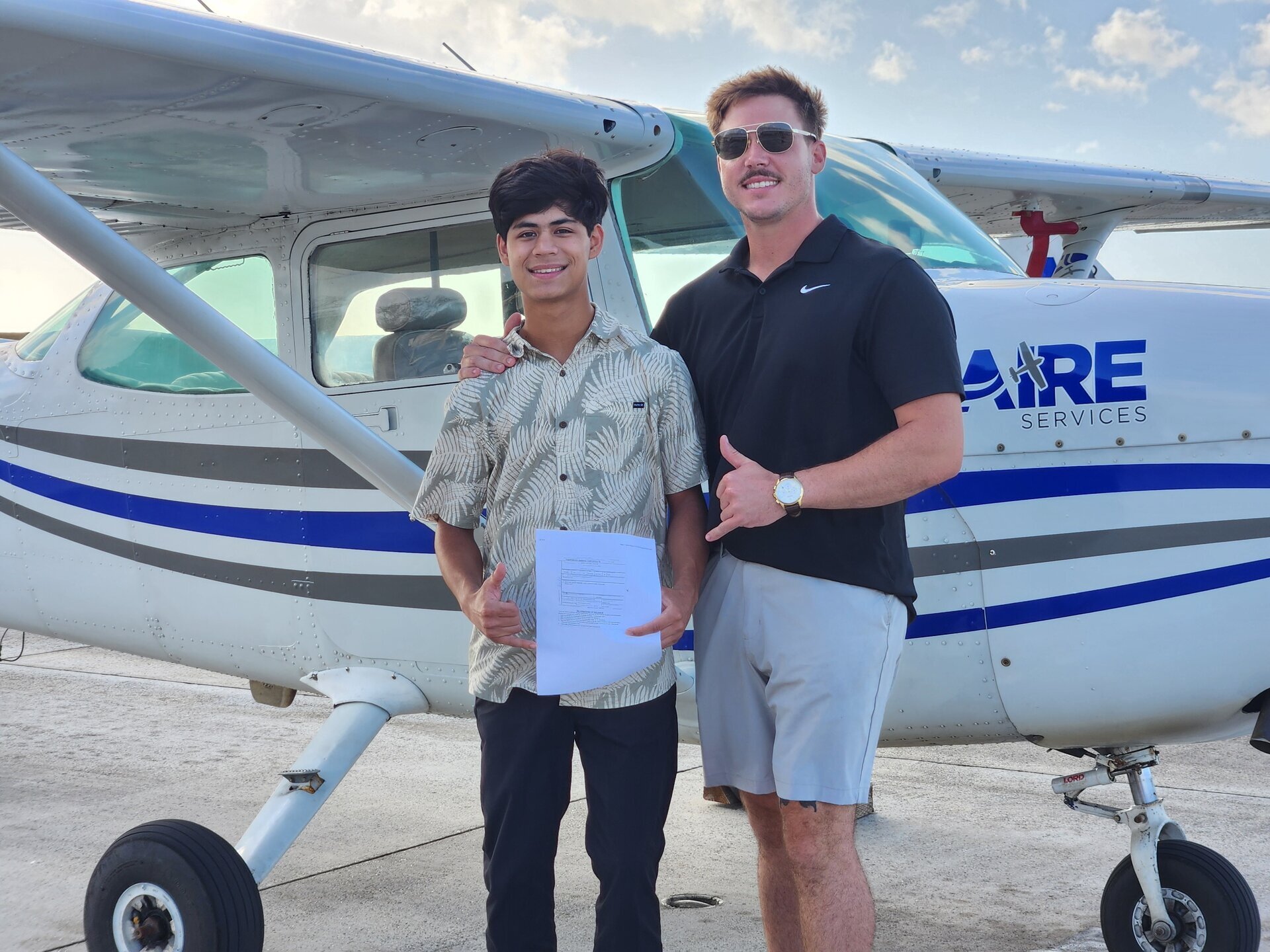 Jaden and instructor Brandon holding solo certificate in front of Cessna N62195